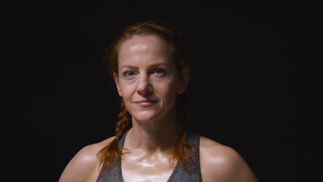 Studio-Portrait-Of-Mature-Woman-Wearing-Gym-Fitness-Clothing-Sweating-After-Exercise